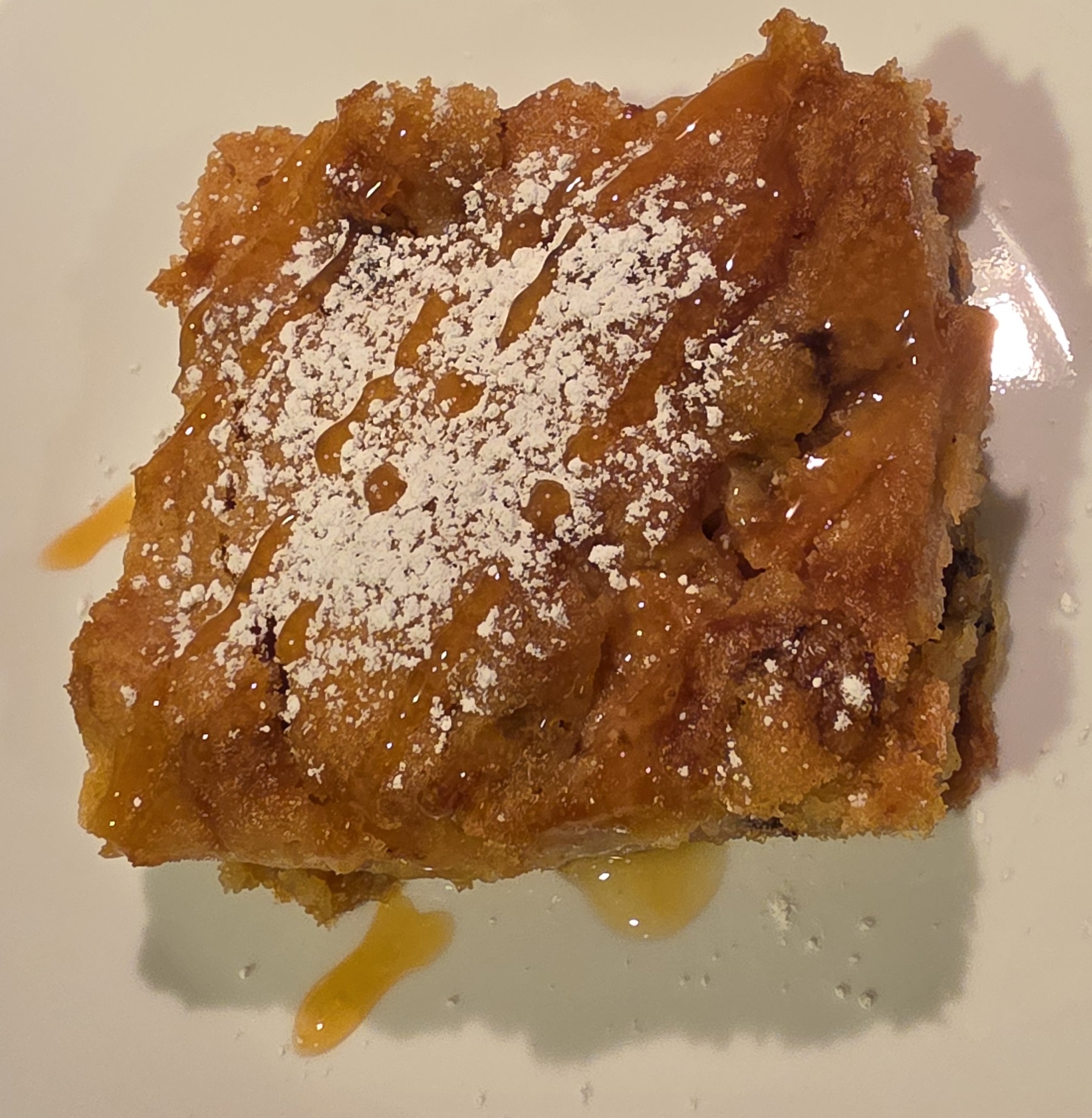 Slice of Apple cake with powdered sugar and caramel drizzle